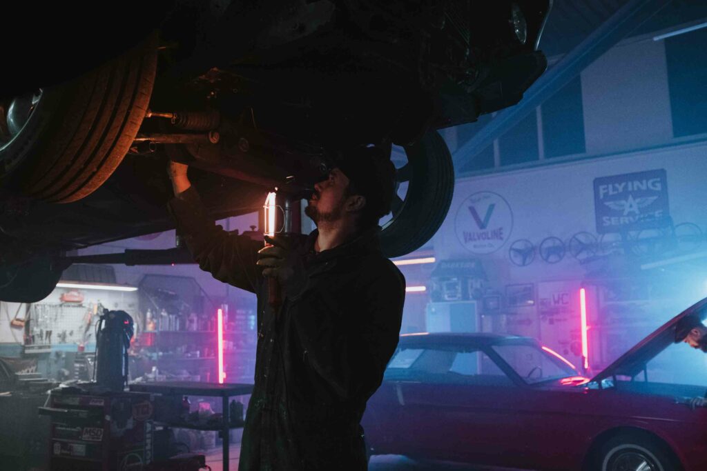 Mehaanik kontrollib auto põhja ja vedrustust tõstukil